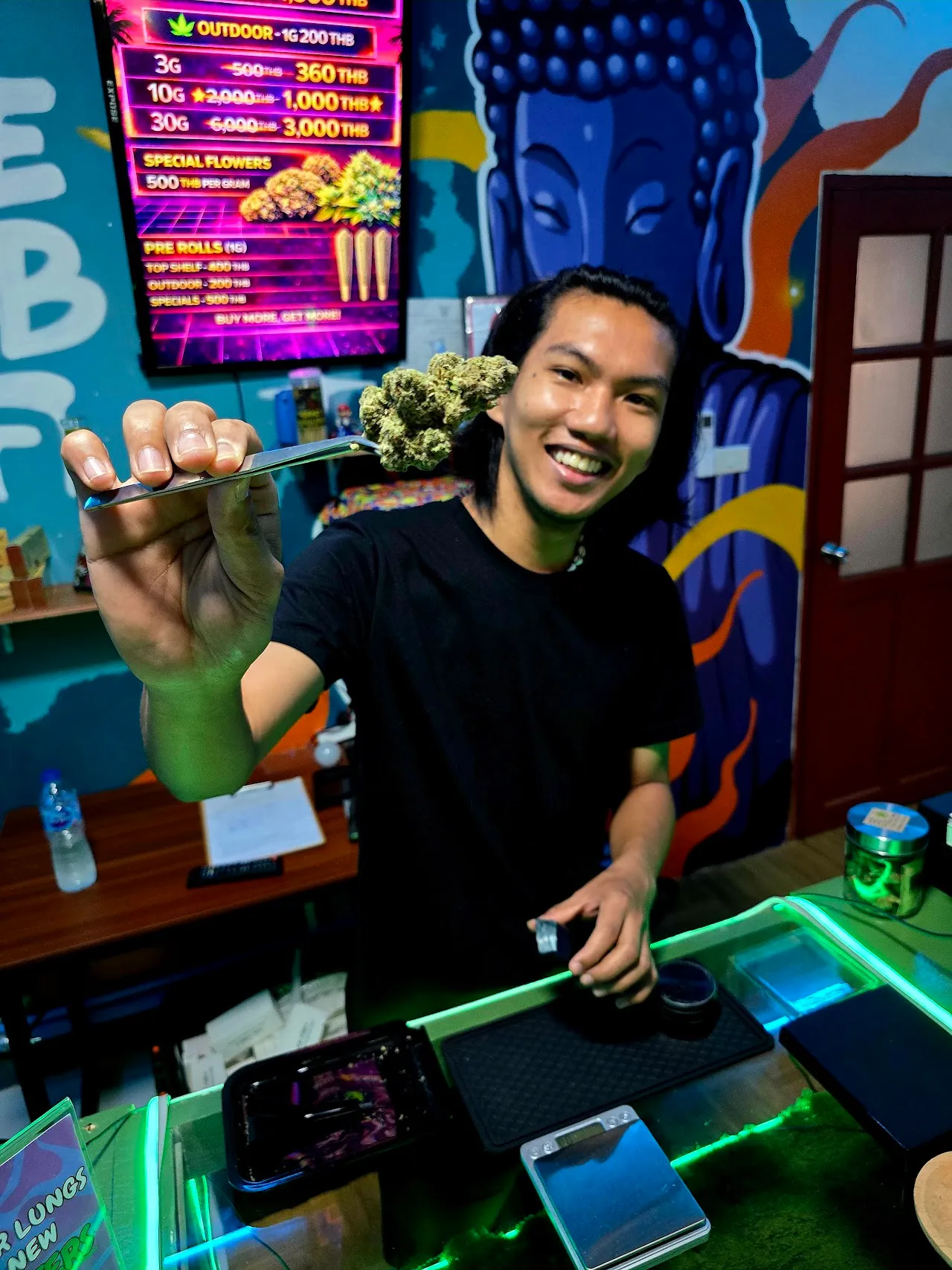 A Hub team member showing fresh house cannabis at the Ao Nang café